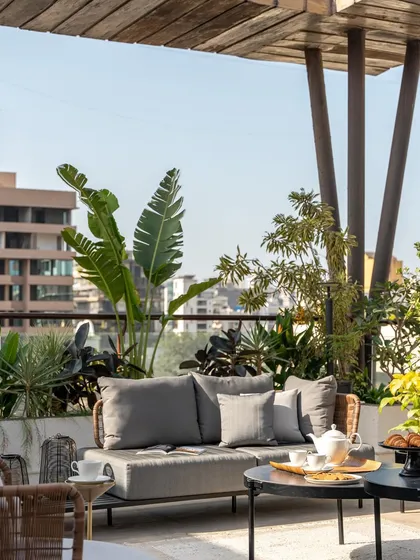 The terrace is furnished with comfortable, weather-resistant furniture, making it a practical and stylish space for year-round enjoyment. The lush planters add a touch of nature and privacy.