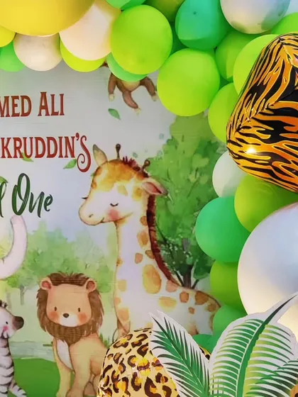 A close-up of a "Wild One" jungle theme backdrop, featuring cute cartoon animals and a tiger-print foil balloon.
