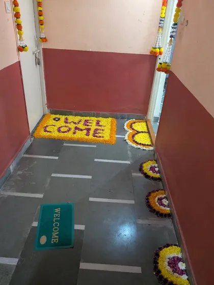 This image shows the complete entrance decor, with the floral "WELCOME" mat and other rangoli patterns lining the hallway. We also added hanging floral garlands to the doorframe for a fully festive entryway.