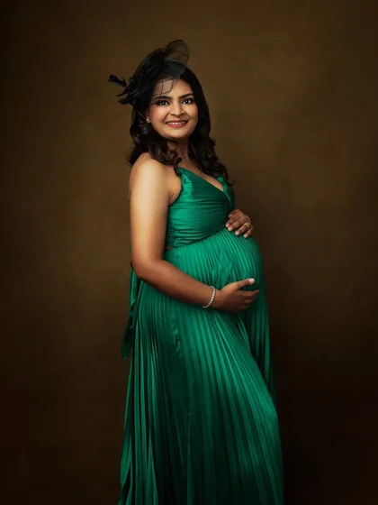 Dressed in a vibrant emerald green, this mother-to-be shines. The simple fascinator adds a touch of classic style to her look.