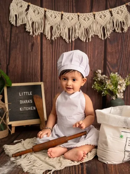 Our little chef is ready for her close-up. The rustic wooden backdrop and macrame details give this baby chef theme a warm, bohemian feel.