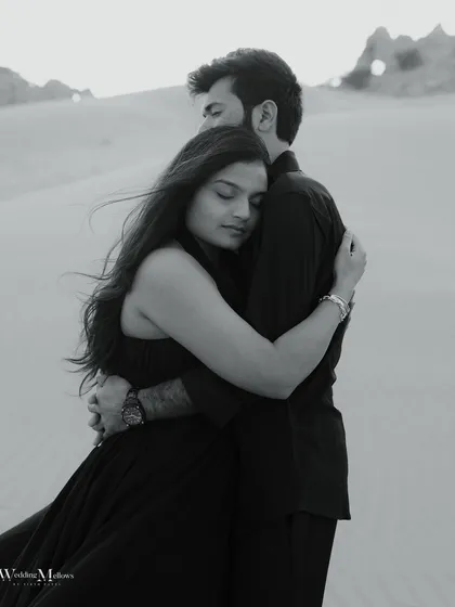 An intimate black and white embrace in the Dubai desert. The soft focus and close crop emphasize the feeling of comfort and safety in each other's arms.