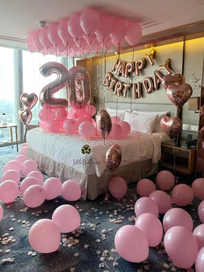 A pretty in pink setup for a 20th birthday celebration. This hotel room decoration features various shades of pink and rose gold balloons, creating a fun and feminine surprise.