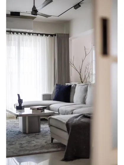 The living room of the 'YBJ Residence' is all about cozy elegance. The generously sized custom sofa is upholstered in a soothing grey boucle fabric, perfect for unwinding.