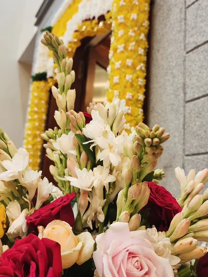 A beautiful bouquet of roses and tuberoses, with a decorated door in the background.