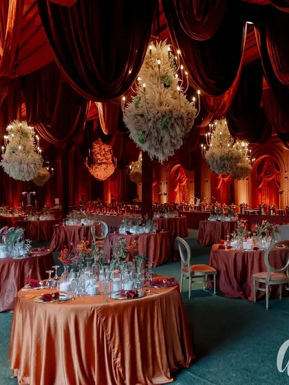 We transformed this space into a dramatic and opulent reception hall using a rich, red color palette and luxurious velvet draping. The scene is set with dozens of floral chandeliers, creating a warm, intimate, and truly grand atmosphere for an evening celebration.