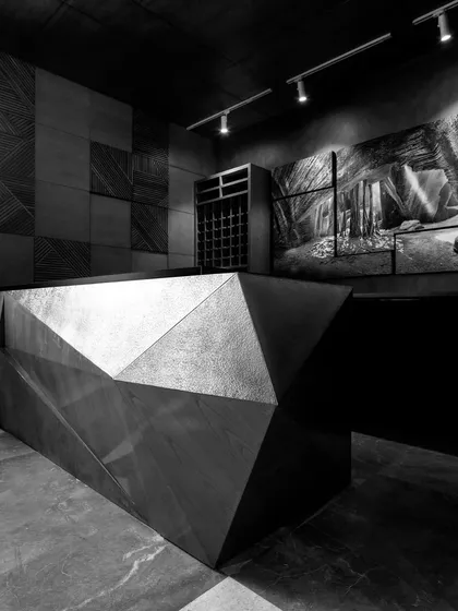 The modern, cubism-inspired bar, designed by us and executed in brass. This dramatic, sculptural piece serves as the restaurant's focal point, set against a backdrop of patterned wood panels and art.