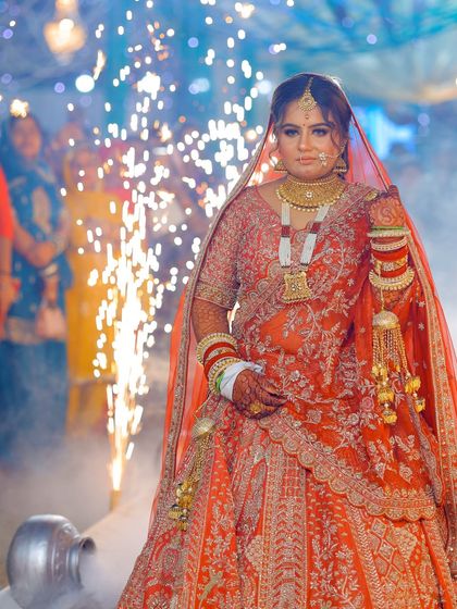 A powerful bridal entry shot with sparklers in the background, creating a celebratory and grand atmosphere.