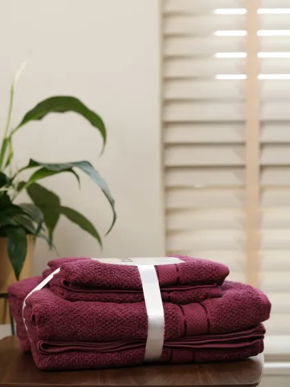 A set of maroon towels in the same serene bathroom setting. We shoot product variations consistently to ensure a cohesive look for your e-commerce store.