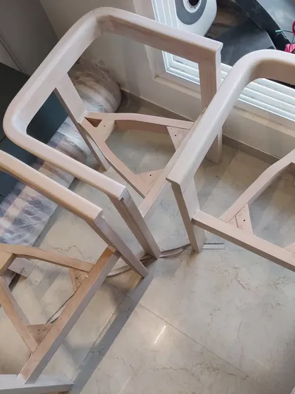 The raw, unfinished frames of dining chairs for our 'Cedar' residence. We oversee every step of the furniture-making process to ensure the highest quality.