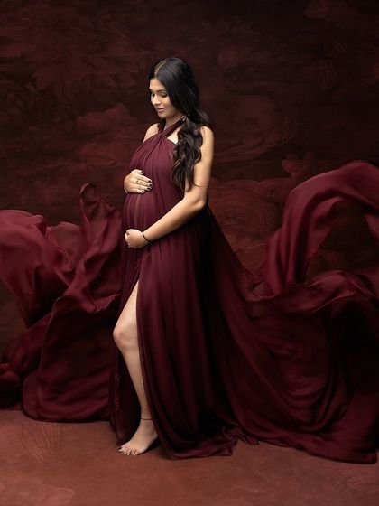 Pure magic in a single frame. This flowing maroon gown and artistic backdrop come together to tell a story of strength, beauty, and the powerful love of a mother.