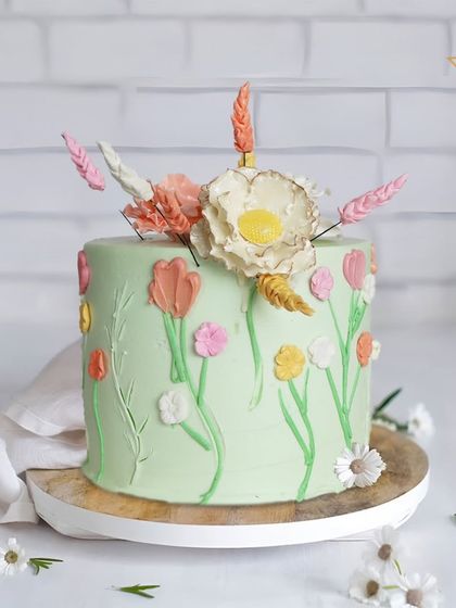 A floral fantasy cake for Riya's celebration in Sainik Farms. This cake features hand-piped pastel tulips and is topped with dried botanicals for a modern, bohemian-inspired garden look.