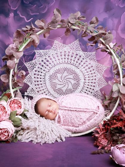 A dreamy purple-themed setup for a twin photoshoot, with one baby resting in a beautiful macrame swing. We design elaborate sets that can accommodate one or both babies.