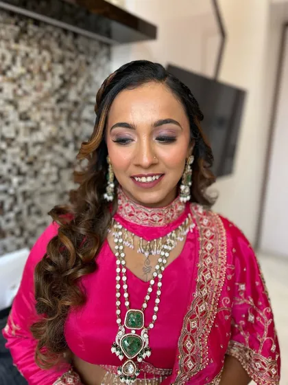 A gorgeous look for a wedding guest. The shimmery eyeshadow and perfectly curled hair complement her bright pink outfit and stunning jewelry.