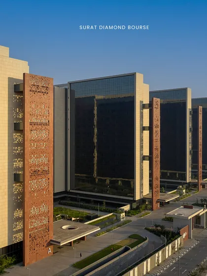 The nine interconnected towers of the Surat Diamond Bourse are oriented to maximize self-shading and promote airflow. This image showcases the scale of the project and the use of 'jaali' screens on the facade, a modern take on a traditional climate-responsive element.