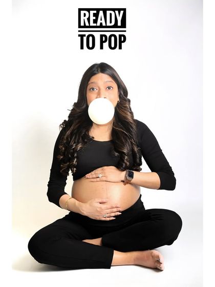A quirky and fun "Ready to Pop" portrait. The mom-to-be is dressed in all black, which makes the bubblegum and her playful expression the focus of this minimalist shot.