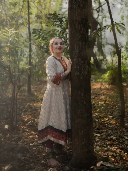 A full-length portrait of the dancer interacting with her natural surroundings. Her gentle pose against a large tree trunk creates a harmonious and peaceful image.