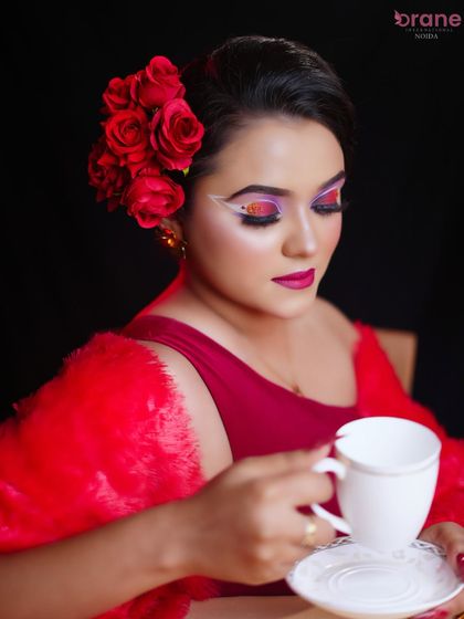 The teacup prop adds a touch of whimsy to this dramatic and glamorous makeup look.