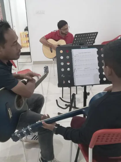 A group guitar lesson in progress. Students learn not only from the instructor but also from each other.