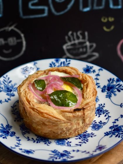 Our Mutton Pepper Fry Puff Pie, a hearty and flavourful weekend special. It's topped with a perfectly cooked egg, pickled onions, and crispy curry leaves.