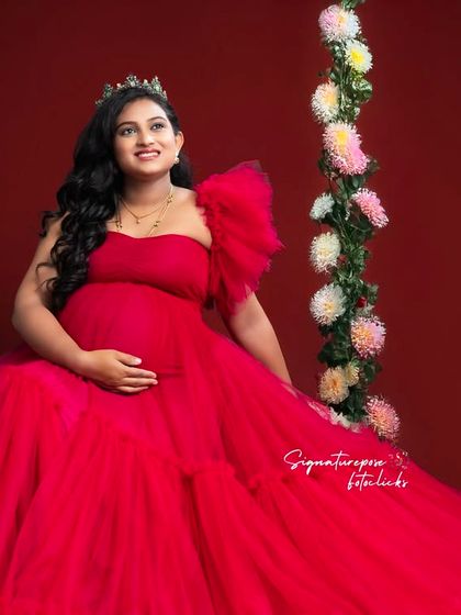 The floral swing and red gown create a beautiful, color-rich composition that feels both elegant and joyful.