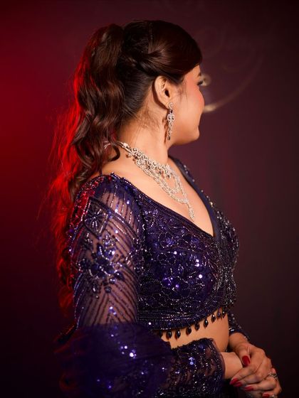 A side view of the purple lehenga, highlighting the intricate sequin work on the long sleeves and the delicate tassels on the blouse.