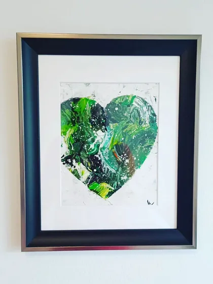 A framed green textured heart, hung on a clean white wall. This is a simple, powerful way to display a piece of art, letting the colors and textures speak for themselves.