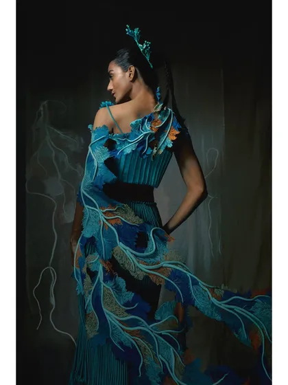 This Vaishali S. piece features vibrant blue and orange embroidery that resembles coral reefs. The styling of the pose from the back highlights the cascading detail of the garment.