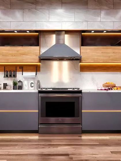 This modern kitchen features handle-less grey cabinets with a thin gold accent line for a touch of elegance. We used wood for the open shelving and integrated warm lighting to create a sophisticated and inviting atmosphere.