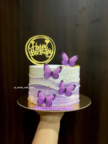 A hand-held shot of the purple ombre butterfly cake, personalized for Janhavi.