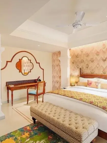 The bedroom in a premium suite at IHCL Pilibhit House, where I used a custom-designed wallpaper and a rich mix of textiles. The space tells a story of grandeur, with a carved wooden desk and an upholstered bench adding to the room's character.