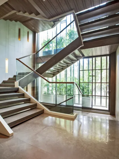 The main staircase is the heart of the home. We positioned it strategically to invite natural light through a screened glass facade, balancing openness with privacy and creating a powerful dynamic that connects the inside to the greenery outside.
