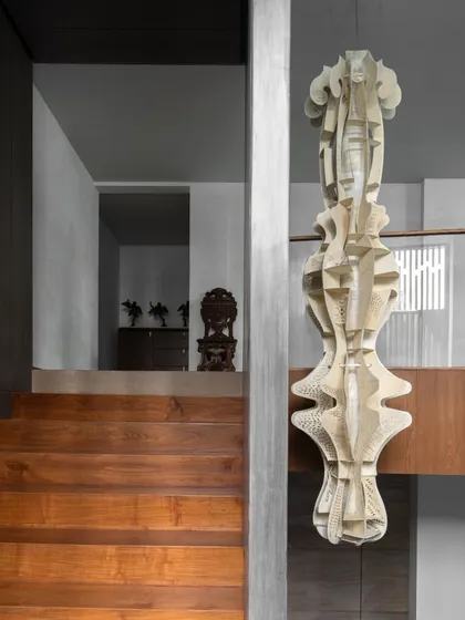 An origami-inspired totem light made from parchment, suspended in a triple-height atrium. This piece introduces a sense of softness and movement into a large architectural void, acting as both a light source and a sculpture.