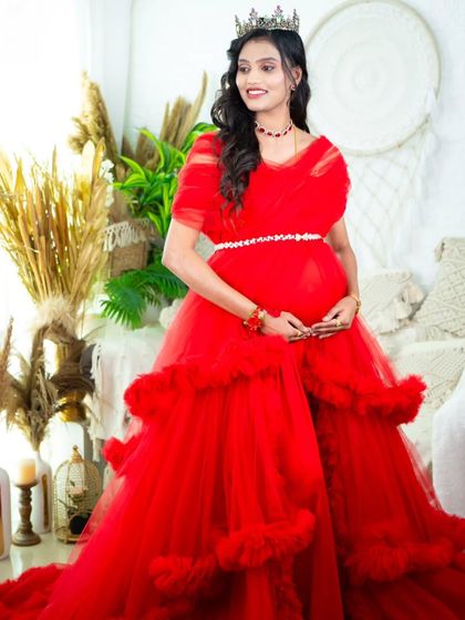 A bright and joyful portrait in a red ruffled gown. The mom-to-be stands in our studio, surrounded by candles and pampas grass, exuding happiness.