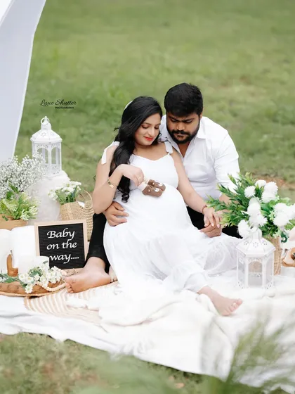 Let's celebrate your new beginning with a beautiful outdoor picnic session. This setup is perfect for capturing sweet, candid moments with your partner, incorporating fun props like baby shoes and announcement signs for a personal touch.