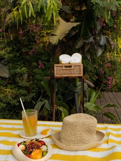 A perfect poolside setup for a slow afternoon: a healthy salad, a cool drink, and a sun hat.