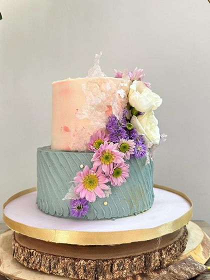 This angle showcases the full floral arrangement on the anniversary cake, with a mix of daisies, roses, and other seasonal blooms creating a lush, garden-like effect.