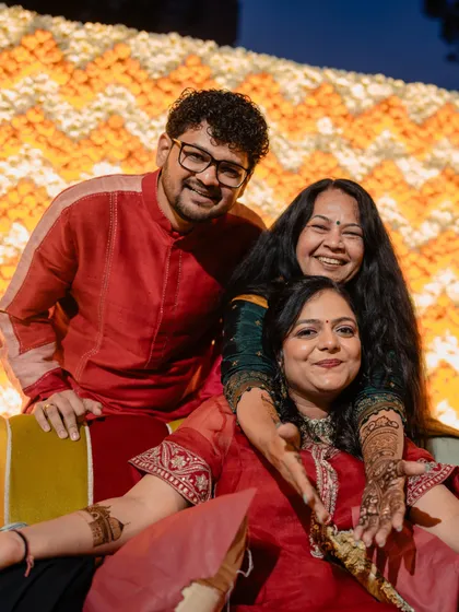 A happy family moment from the mehendi. The coordinated red and earth tones of the outfits create a warm, festive atmosphere that is perfect for the occasion.