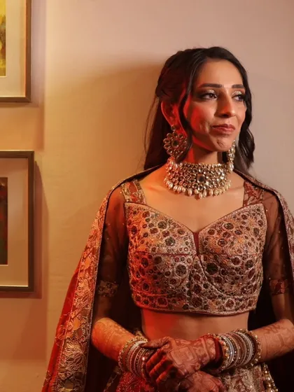 A soft and elegant engagement look. The hairstyle features gentle waves and a simple twist, complementing her intricate outfit and pearl choker beautifully.