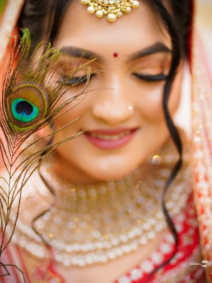 A close-up of the bride's face, with a peacock feather gently brushing her cheek. This creative and symbolic shot is both beautiful and unique.