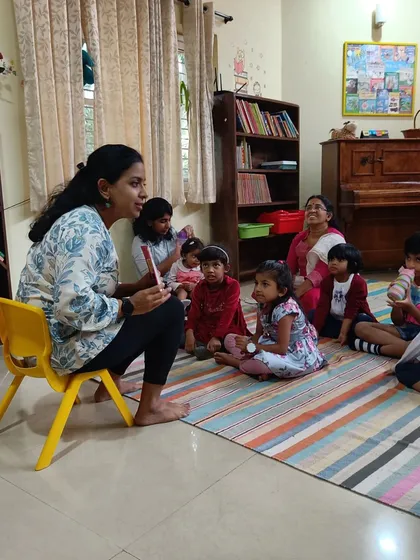 A storyteller engages with the children, asking questions about the adventurous swimming journey of a baby ghariyal. This interactive approach helps build comprehension and confidence.