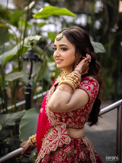 A beautiful candid of the bride in her red lehenga. The soft, open hairstyle gives a modern touch to the traditional outfit.