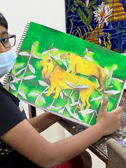 The proud student holding his completed lion drawing, showcasing a vibrant green background that makes the yellow lions pop.
