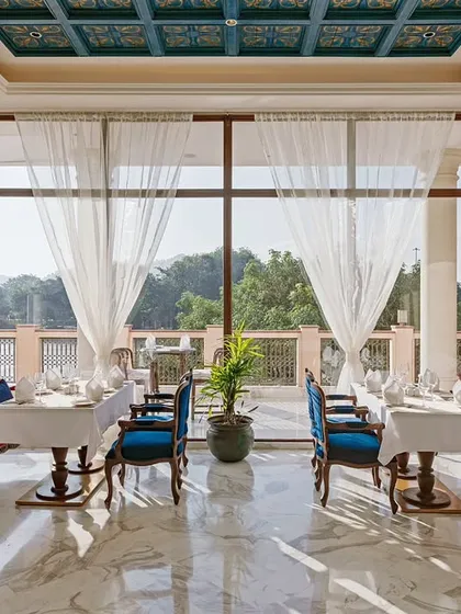 Sunlight streams through sheer curtains in this dining space at IHCL Pilibhit House. I designed this area to feel bright and airy, using a mix of fuchsia and royal blue upholstery to add a touch of playful luxury against the serene, natural backdrop.