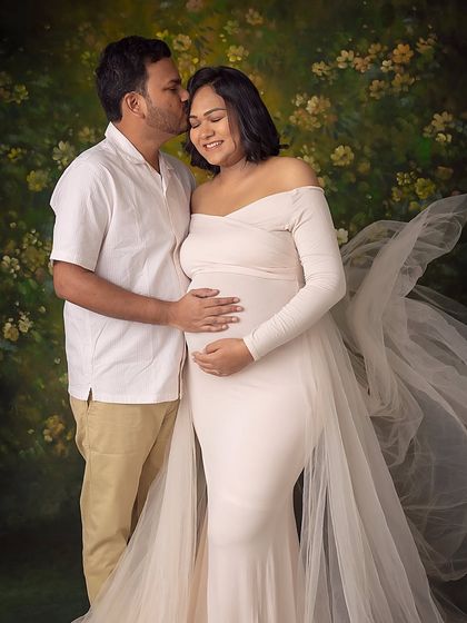 A warm embrace against a painterly floral backdrop. The partner's kiss on her forehead adds a layer of love and security to the portrait.