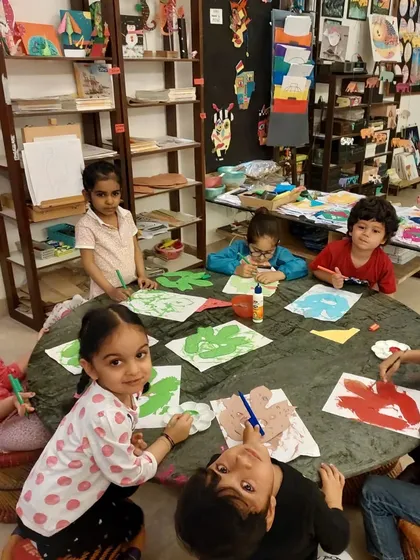 A group of young students working on their "Do" masks, using paint and collage to create fierce and protective faces.