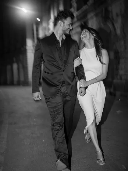 A candid moment of laughter between a couple during a nighttime city shoot, captured in timeless black and white.