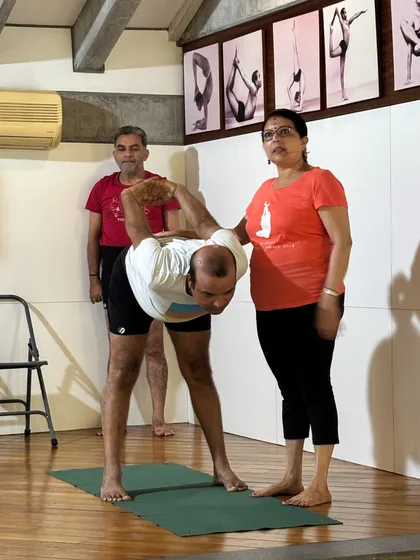 Good health is a gift. Our beginner classes give you the tools to cross your limitations and feel rejuvenated. This image shows me correcting a student's alignment in a standing forward bend, a fundamental pose for beginners.