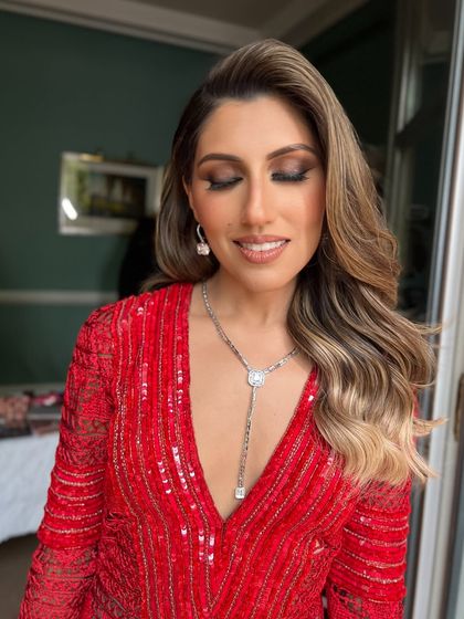 A bride in a stunning red dress, her highlighted hair styled in soft, beachy waves for a destination wedding event in Spain.