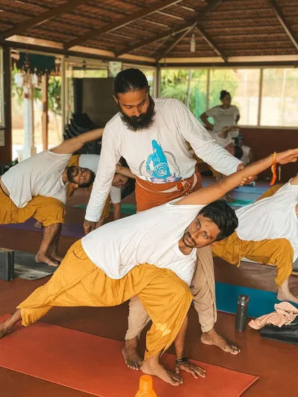 I believe in guiding each student personally. Here, I am offering a gentle adjustment in a forward fold, helping the student to find space and release tension safely. My approach is to meet you where you are, with patience and support, so you can trust your body and deepen your practice without force.